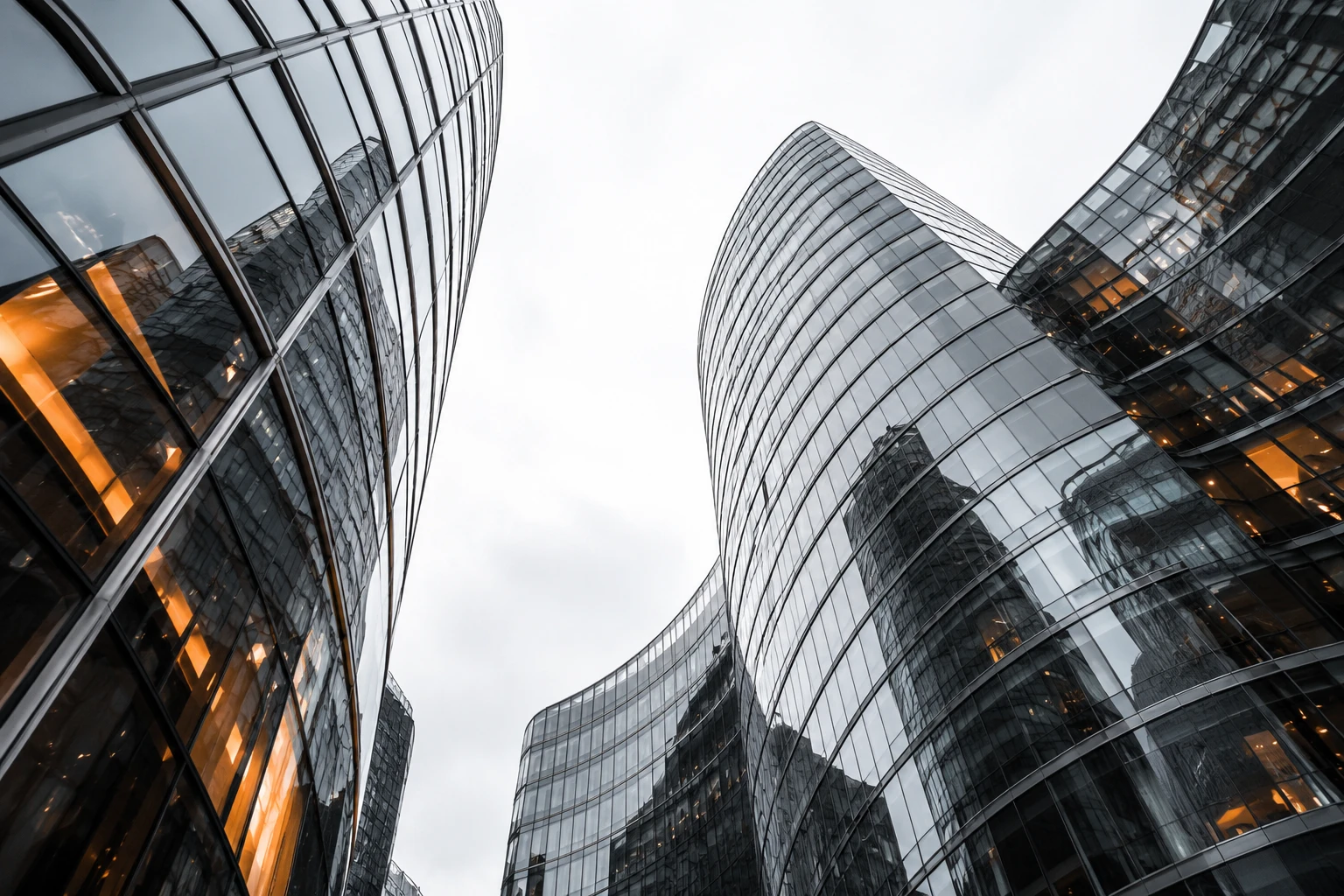 Glass and steel towers viewed from below, opening toward the sky